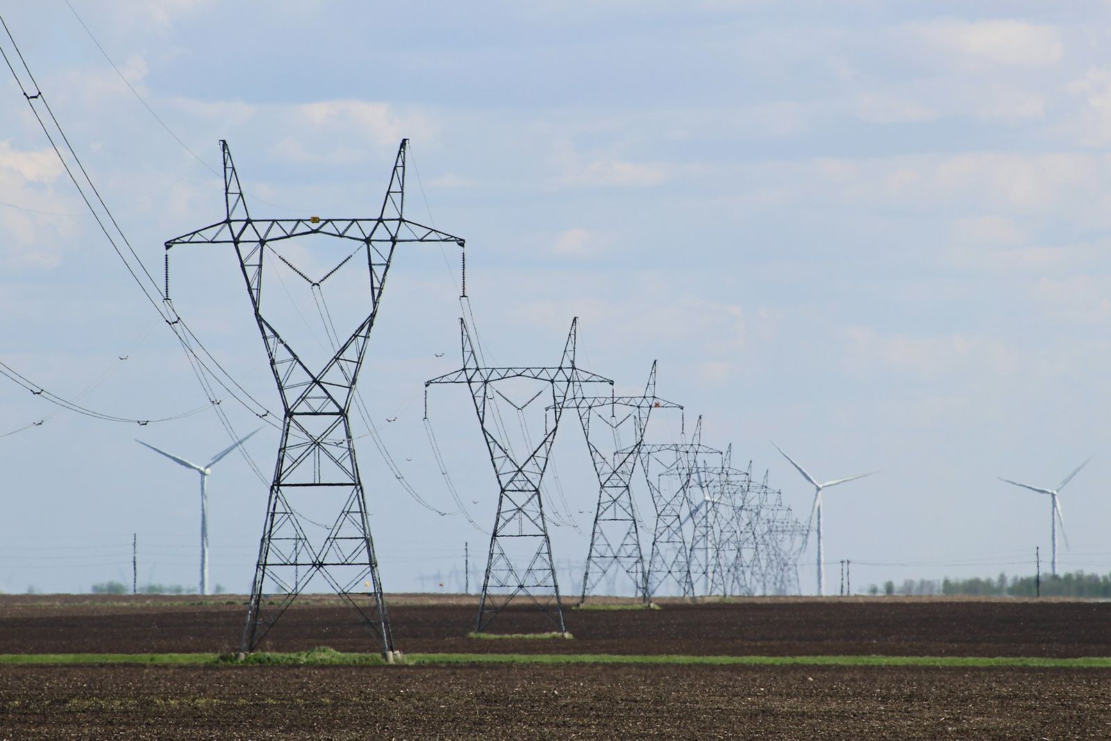 High-voltage transmission towers across open farmland